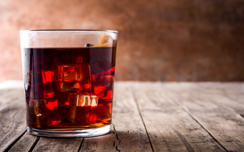 A glass of boulevardier on a wooden surface