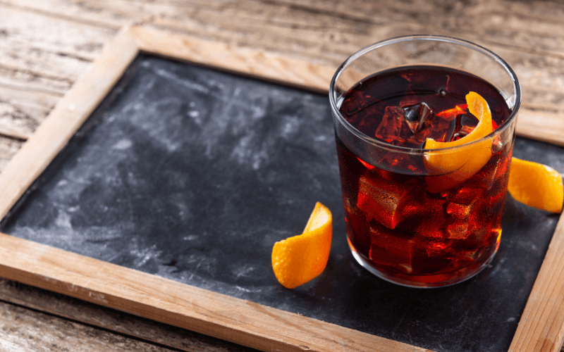 A glass of boulevardier on a wooden surface
