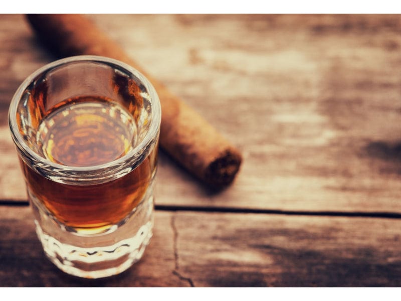 A glass of bourbon with a cinnamon stick