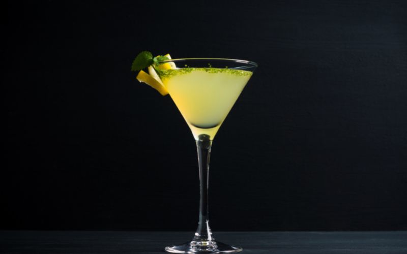 A glass of good luck charm cocktail on a dark background