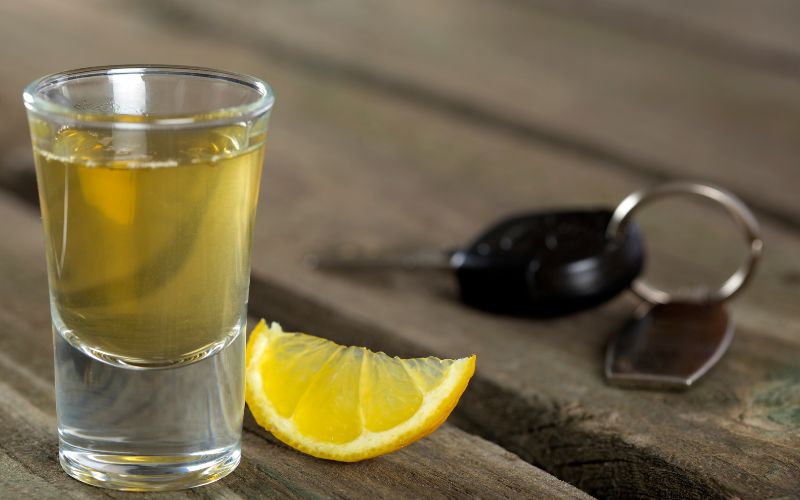 A glass of honey citrus drop shooter on a wooden surface