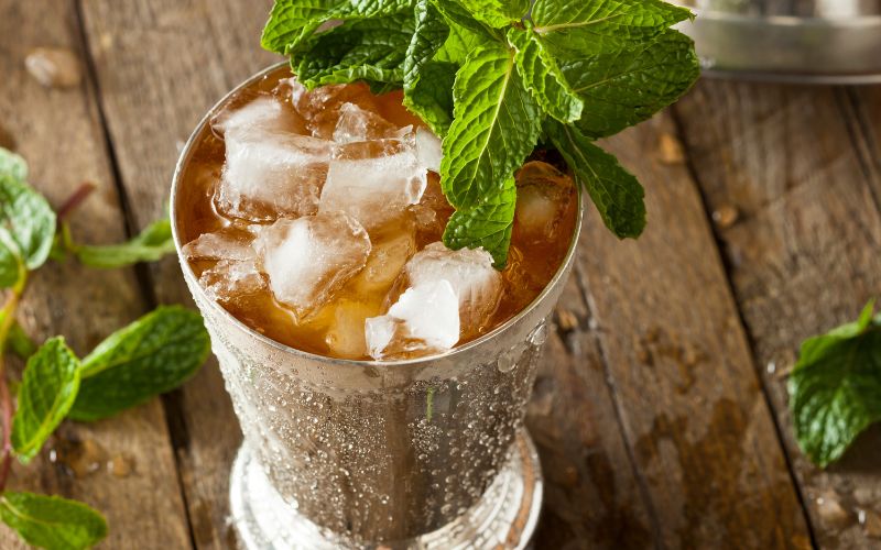 A glass of peach beer julep on a wooden surface