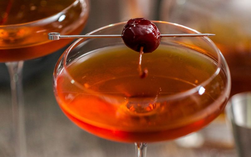 A glass of perfect Manhattan cocktail on a wooden surface