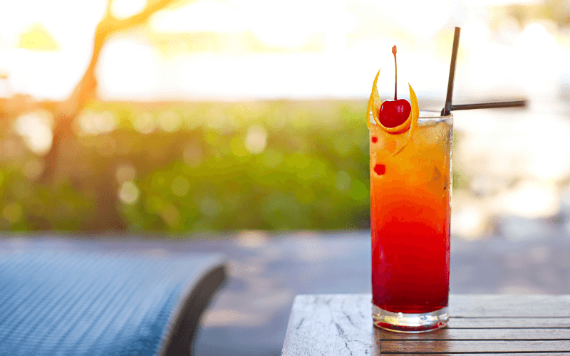 A glass of sparkling peach sunrise with cherries and oranges