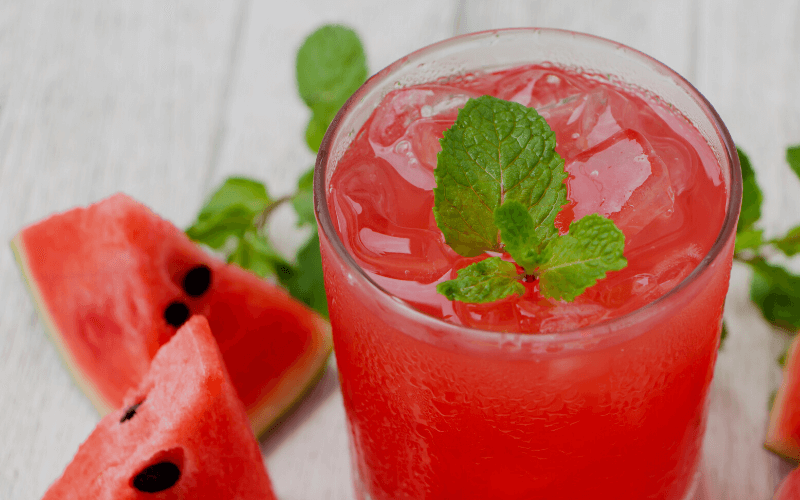 A glass of watermelon tequila punch garnished with mint leaves