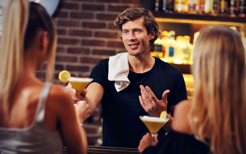 A male bartender chatting with customers