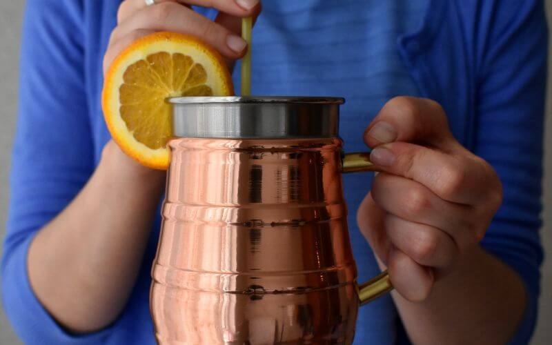 A man sipping a drink from a copper mug