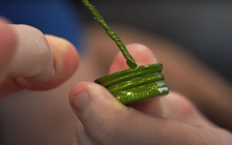 A person flicking a Soju cap