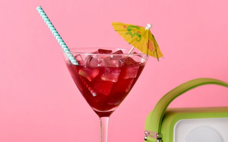 A red cocktail garnished with a paper umbrella