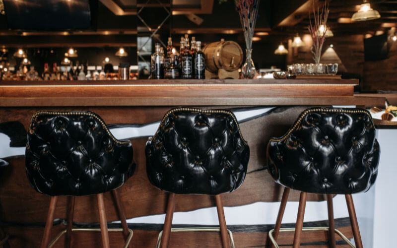 A rustic bar with black bar stools