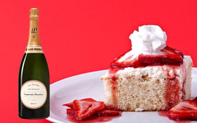 A slice of strawberry shortcake and a bottle of champagne