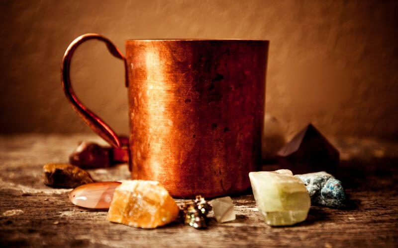 A slightly oxidized copper mug with a gemstones