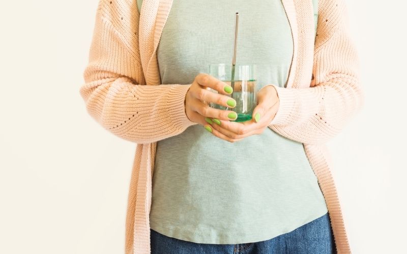 A woman holding glass with a reusable metal straw
