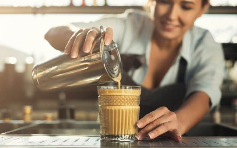 A woman pouring coffee cocktail onto glass