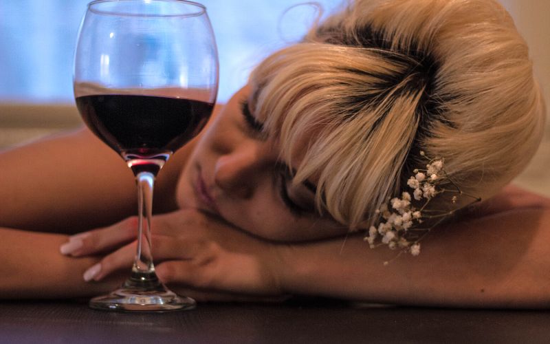A woman sleeping beside a wine glass