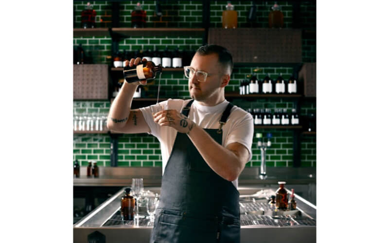 Alex Kratena pouring a liquor into a cocktail glass