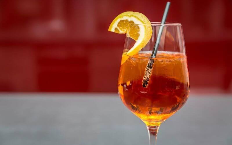 Aperol spritz with a straw and a lemon wedge