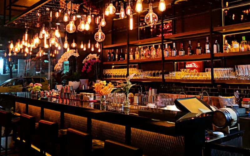 Bar counter filled with bar tools and liquor shelves