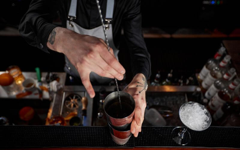 Barman stirring cocktail with a bar spoon