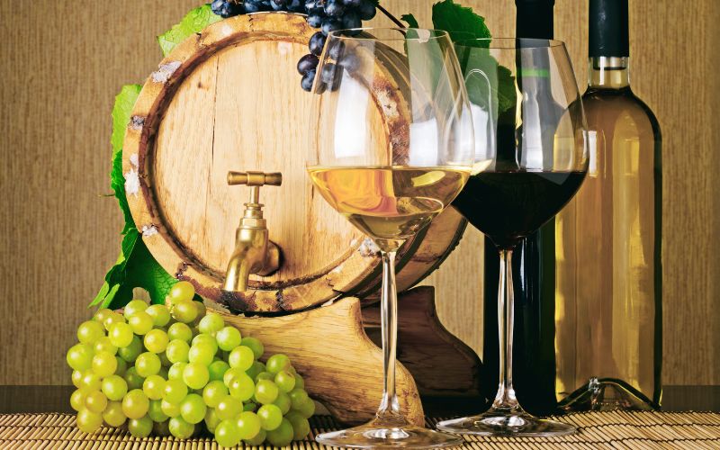 Barrel of wine with glasses, bottles, and grapes