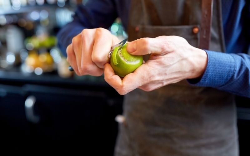 Bartender Removing Peel from Lime at Bar