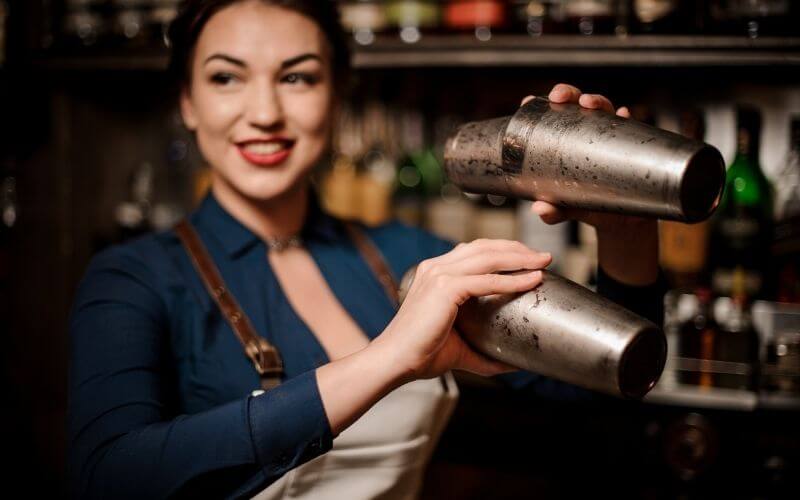 Bartender girl holding two steel cocktail shakers