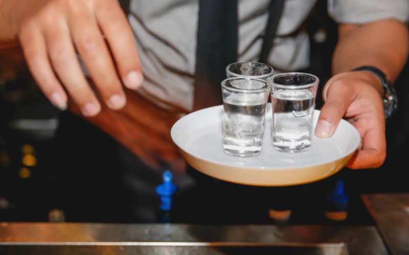 Bartender holding a bowl of tequila shots