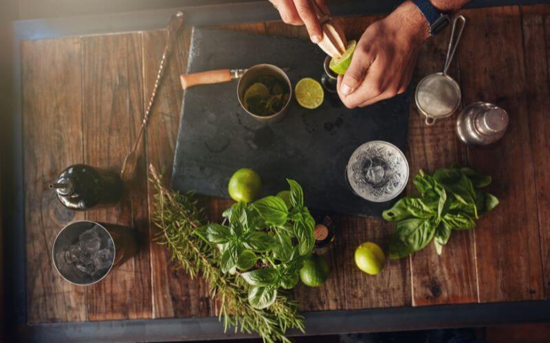 Bartender preparing a cocktail with citrus and herbs