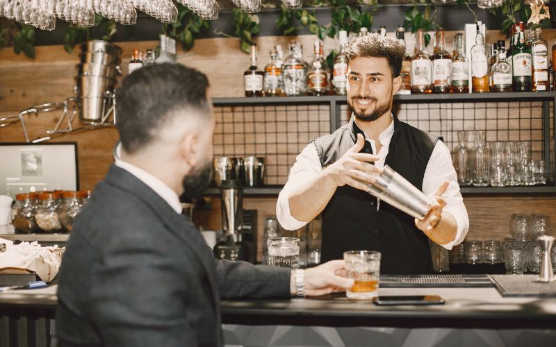 Bartender preparing a drink and talking to a customer