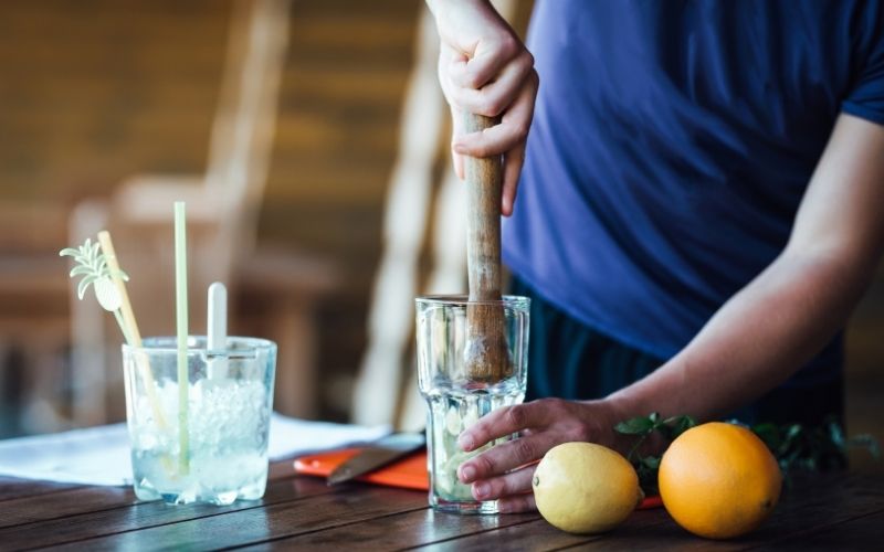 Person muddling ingredients for a cocktail