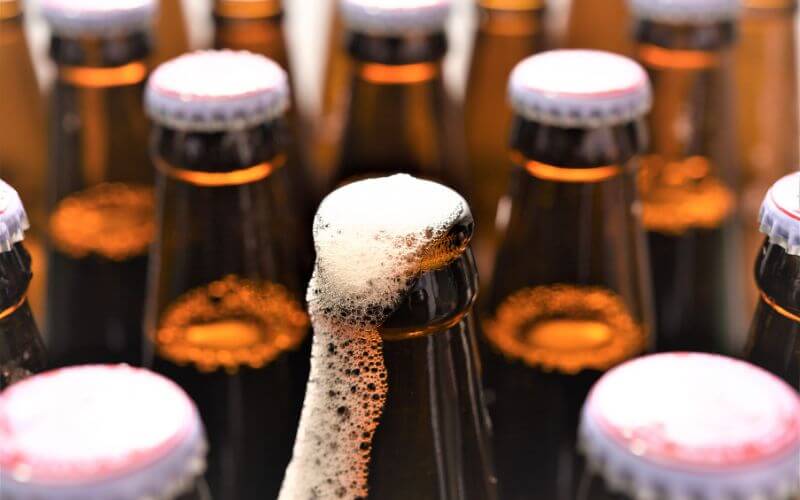 Beer bottles with one opened and foaming