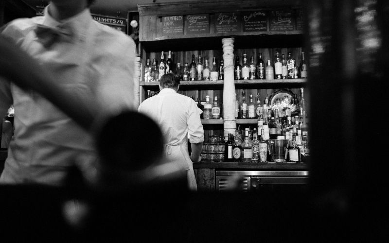 Bartender doing bartending work in front of the wine rack