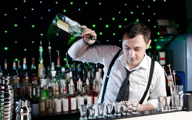 Man pouring liquor onto shot glasses