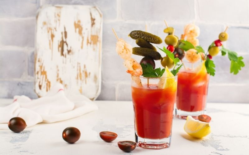 Bloody Mary cocktail garnished with skewered pickles and olives