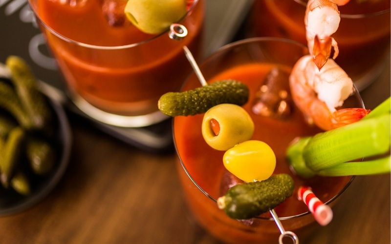 Bloody mary cocktail garnished with pickles and olives