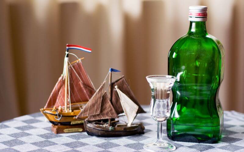 Bottle and glass of Jenever beside tiny boats