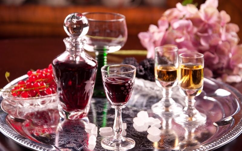 Bottle and glasses of cordial on a tray with cherries and flowers