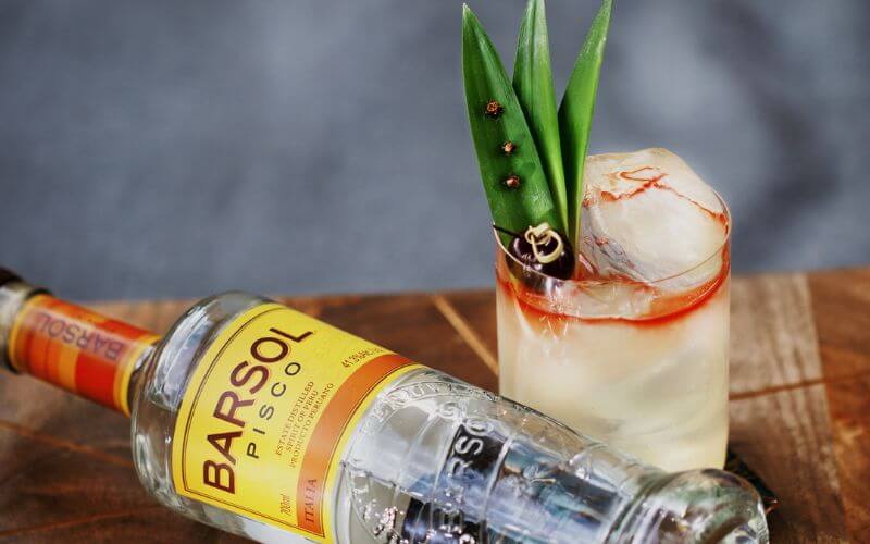 Bottle of Pisco beside a cocktail - Image by Barsol Pisco