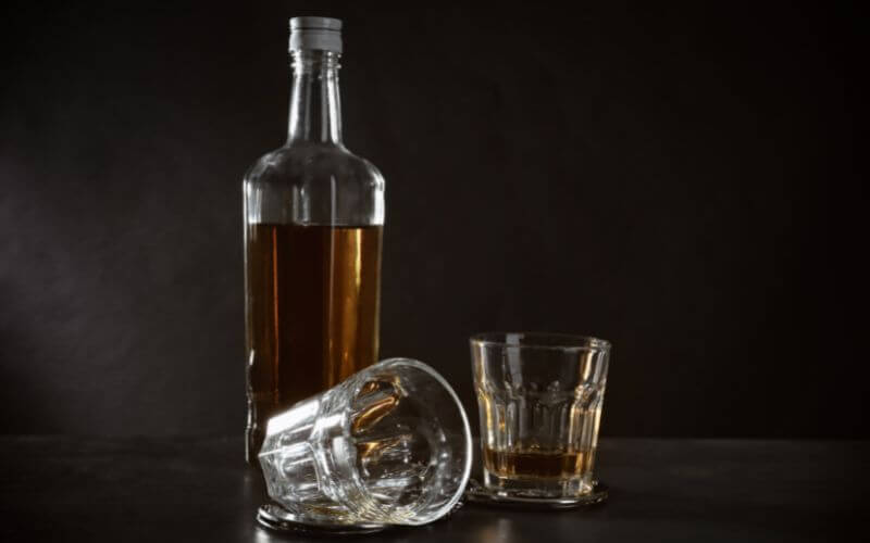 Bottle of Rhum and Glasses with Handcuffs on Dark Background