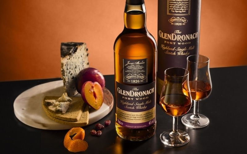 Bottle of Scotch with 2 glasses and cheese on the background