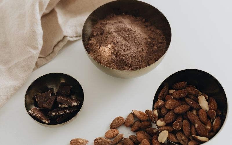 Bowls of cocoa powder, almonds, and chocolate 
