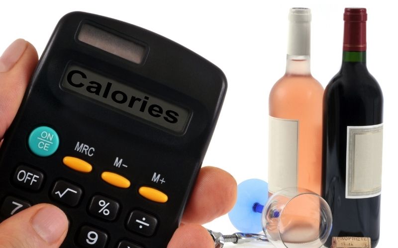 Calculator and wine bottles and glass behind