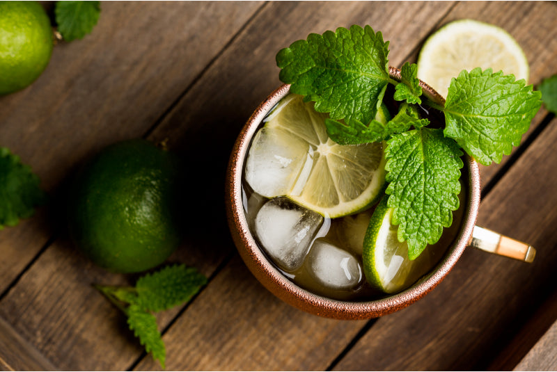 Cold Moscow Mule cocktail in copper mug on rustic background top view