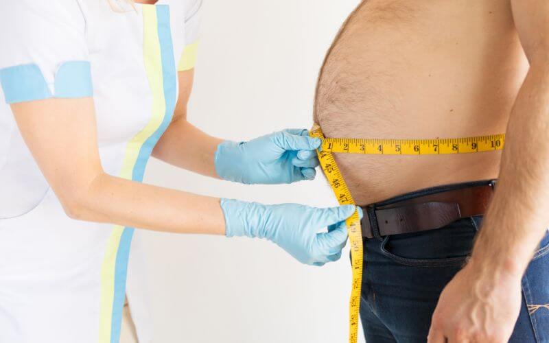Dietician Measuring Man's Stomach Fat Measurements during Checkup