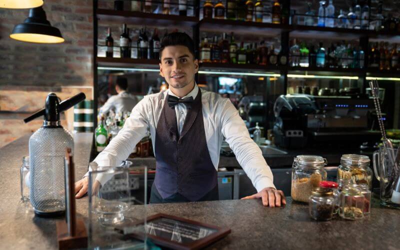 Friendly Bartender Leaning in Bar Counter