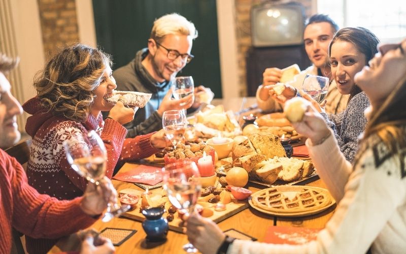 Friends talking, drinking wine, and eating at a table