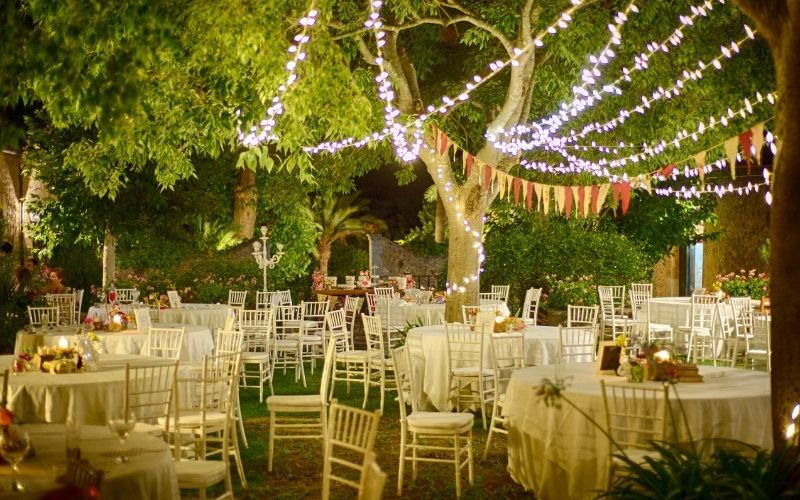 Garden cocktail party with kitchen dining table and chairs and fairy lights