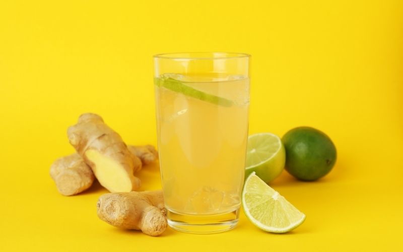 Glass of Ginger Beer with ginger and lime on Yellow Background