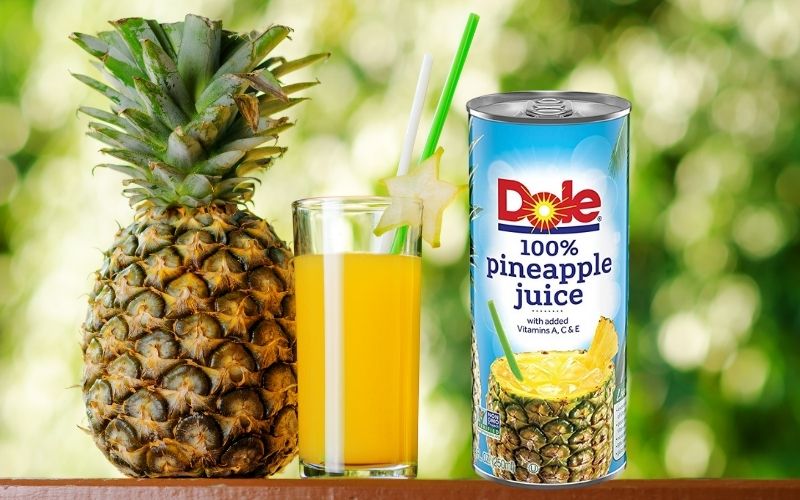 Glass of pineapple juice beside a whole pineapple