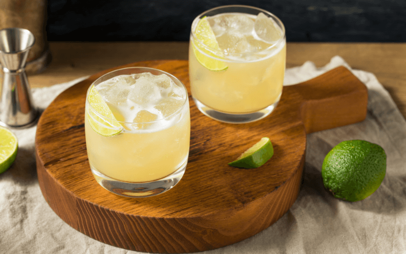 Glasses of Tommy's margarita with lime in a wooden tray